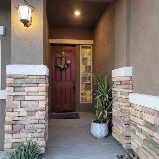 A welcoming front porch entrance with brick accents and potted plants.