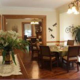 A cozy dining room with a wooden table and chairs, adorned with plants and elegant lighting.