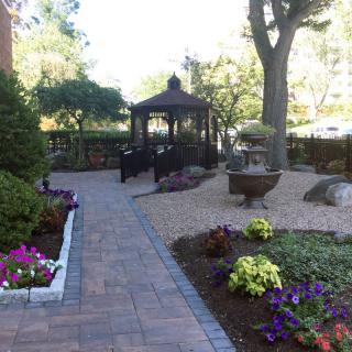 A beautifully landscaped garden featuring a stone pathway, a charming gazebo, and vibrant flowers.