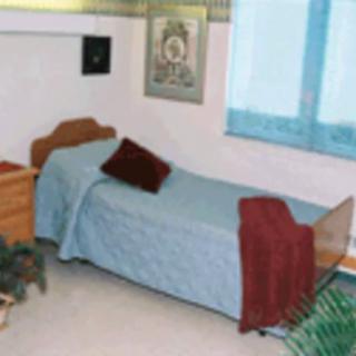 A simple bedroom with a single bed and modest decor.