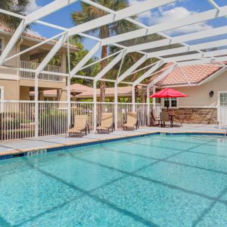 A backyard swimming pool with a protective enclosure, patio furniture, and an umbrella.