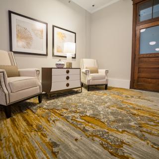 A cozy waiting room with two armchairs, a small table, and abstract artwork on the wall.