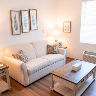 A cozy living room with a white sofa and wooden coffee table, accented by decorative wall art and soft lighting.