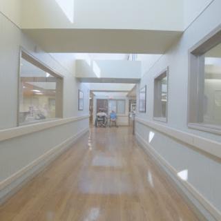 A spacious and well-lit hospital hallway with large windows.