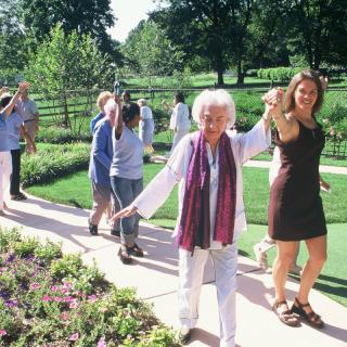 A group of people walking together in a sunny garden.