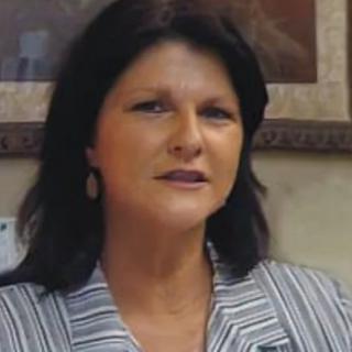 A professional woman indoors wearing a striped shirt.