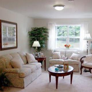 A cozy living room with a sofa, coffee table, and lamps, complemented by natural light from the window.