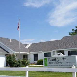 A country-style assisted living facility with a flag and a prominent sign out front.
