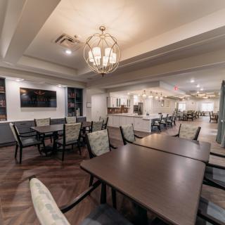 A modern dining area with neatly arranged tables and chairs, featuring elegant chandeliers and a spacious layout.