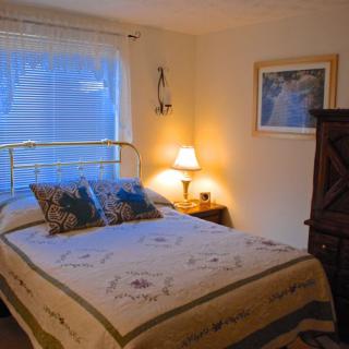 A cozy bedroom with a neatly made bed, soft lighting from a bedside lamp, and decorative elements.