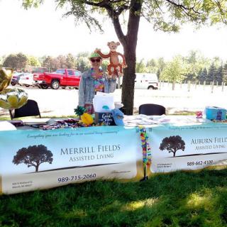 An outdoor information booth set up under a tree during the day, featuring banners and materials on tables.