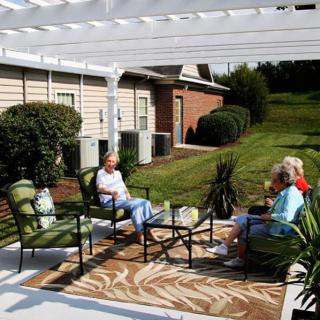 A group of people relaxing on a patio under a pergola with comfortable seating.