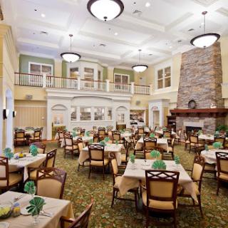 A spacious dining area featuring elegant tables and chairs, adorned with green decor, and a cozy fireplace.