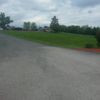 A view of a winding road leading into a grassy area under a cloudy sky.