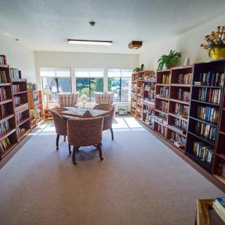 A cozy library with bookshelves and a reading area bathed in natural light.