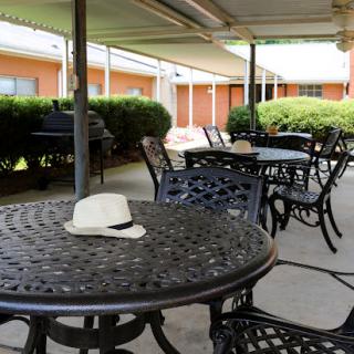 An outdoor seating area featuring black metal tables and chairs, with a white hat resting on one of the tables.