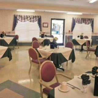 An empty dining room with neatly arranged tables and chairs, featuring decorative curtains.