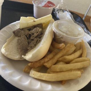 A meal consisting of a sandwich, fries, and sauce on a plate.