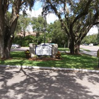 A welcoming entrance featuring a sign surrounded by lush greenery and trees.