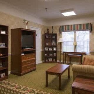 A cozy living room with a television, sofa, coffee table, and bookshelf.