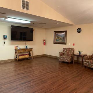 A cozy living room setup featuring comfortable chairs, a wall-mounted television, and wooden flooring.