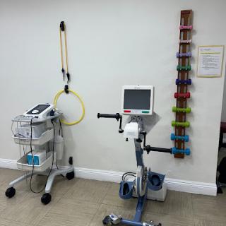 A view of a physical therapy room featuring an exercise bike and various weights.