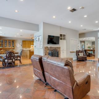 A spacious living room with an open floor plan connecting to the kitchen and dining area, featuring comfortable seating, a fireplace, and a mounted television.