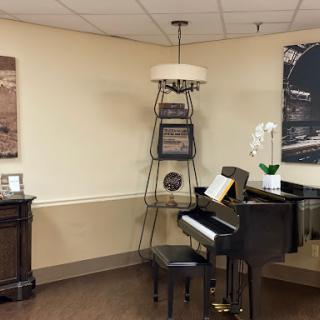 A cozy corner featuring a piano with decorative art and a stylish lamp.