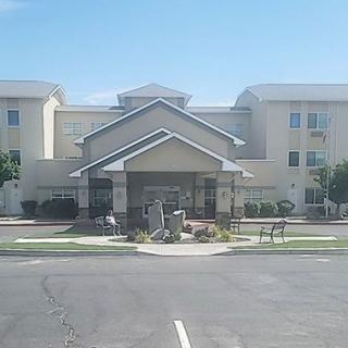 A modern hotel building with an entrance and adjacent parking area.