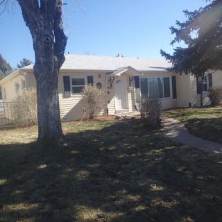 A suburban house with a yard and trees under clear daylight.