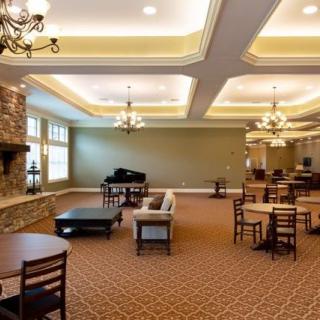 A spacious lounge area featuring a piano, multiple seating arrangements, and elegant chandeliers.