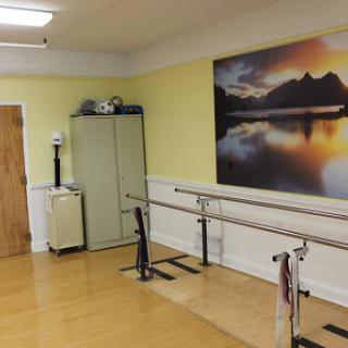A view of a dance studio featuring barre equipment and a serene landscape mural.
