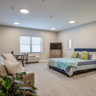 A spacious, modern bedroom with a bed, sofa, and television.
