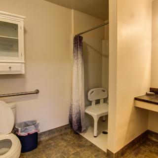 A clean and accessible bathroom featuring a toilet, shower area, and sink.