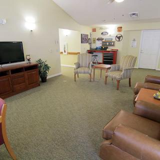 A cozy living room with seating area featuring sofas, chairs, a television, and a carpet.