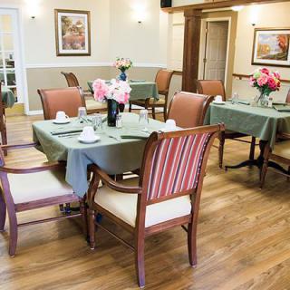 A cozy dining area with neatly arranged tables and chairs, featuring floral centerpieces.