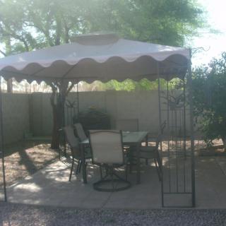 A backyard patio setup with a canopy and outdoor furniture for shaded seating.