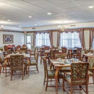 An elegant dining area with neatly arranged tables and chairs, featuring classical decor and lighting.