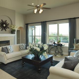 A stylish living room featuring elegant furniture and large windows, with a cozy fireplace as a focal point.