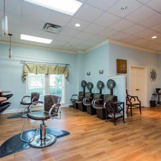 An empty hair salon with styling chairs and hair dryers lined up against a light blue wall.