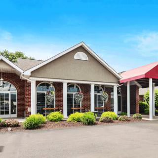 Exterior view of a hotel with an entrance featuring brick walls and a red awning.