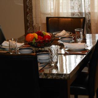 A dining table set with a fruit basket and neatly arranged glasses and napkins.