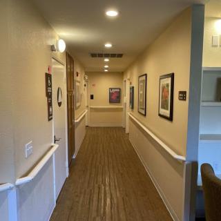 A well-lit hallway with wooden flooring, decorated with framed pictures on the walls.