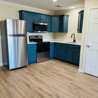 A modern kitchen with blue cabinets and stainless steel appliances.
