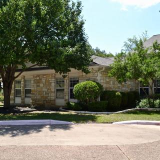 A suburban house with a brick exterior, surrounded by trees and well-maintained landscaping.