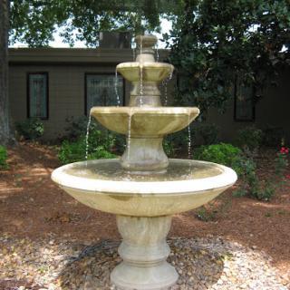 A beautiful tiered fountain surrounded by lush greenery.