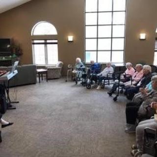 A group of seniors seated indoors for a meeting or gathering.