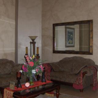 A cozy living room with a sofa, decorative table, and a large mirror.