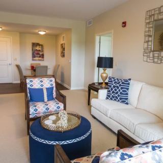 A modern living room featuring a white sofa, patterned armchair, and a stylish coffee table with home decor accents.