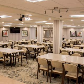 An empty cafeteria with neatly arranged tables and chairs, well-lit interior.